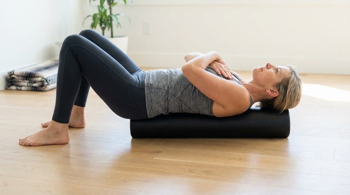 Woman lying on a foam roller performing a thoracic extension exercise to correct posture and reduce dowager’s hump.